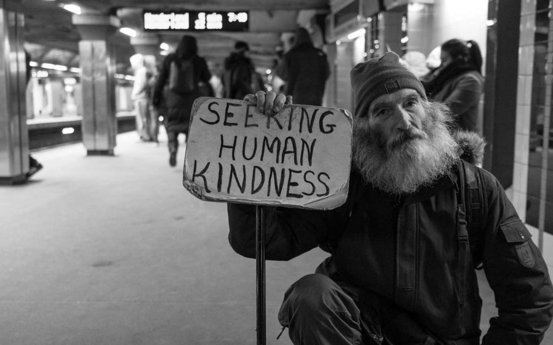 Elderly man with sign "Seeking human kindness"